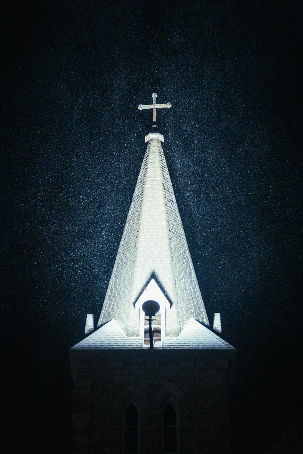 a church steeple lit up at night with a cross on top