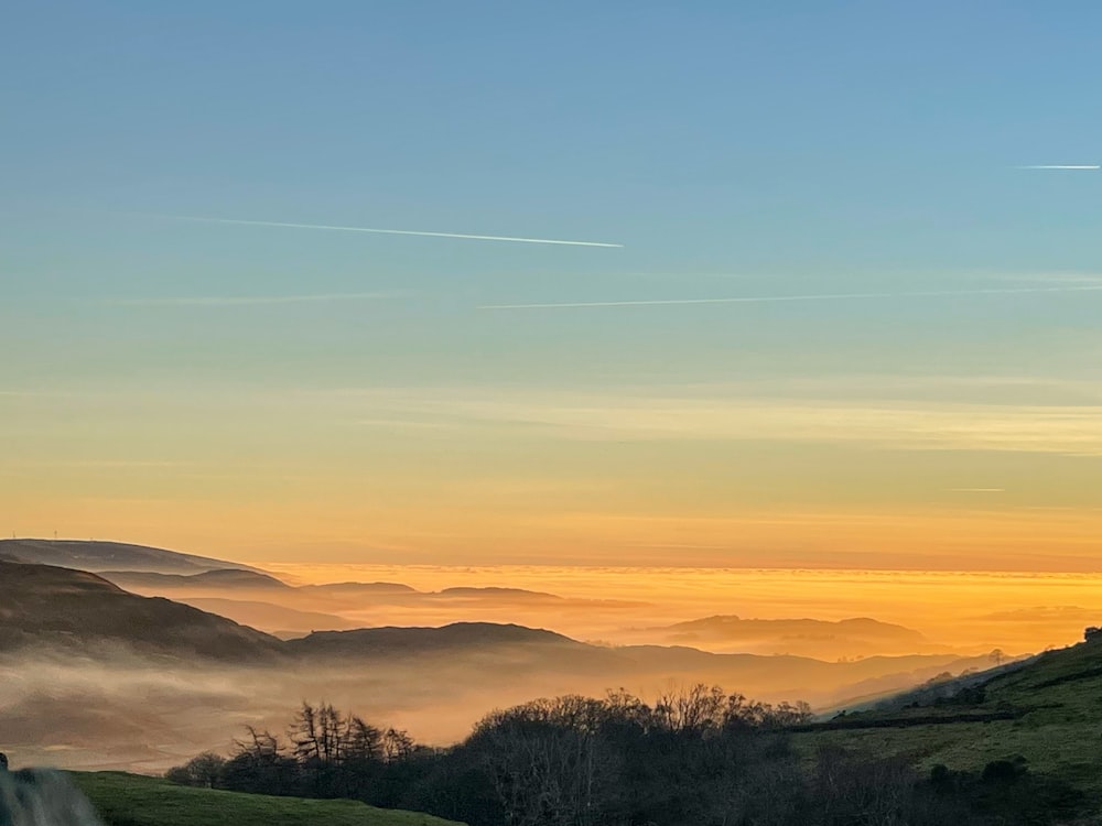 the sun is setting over the hills and valleys