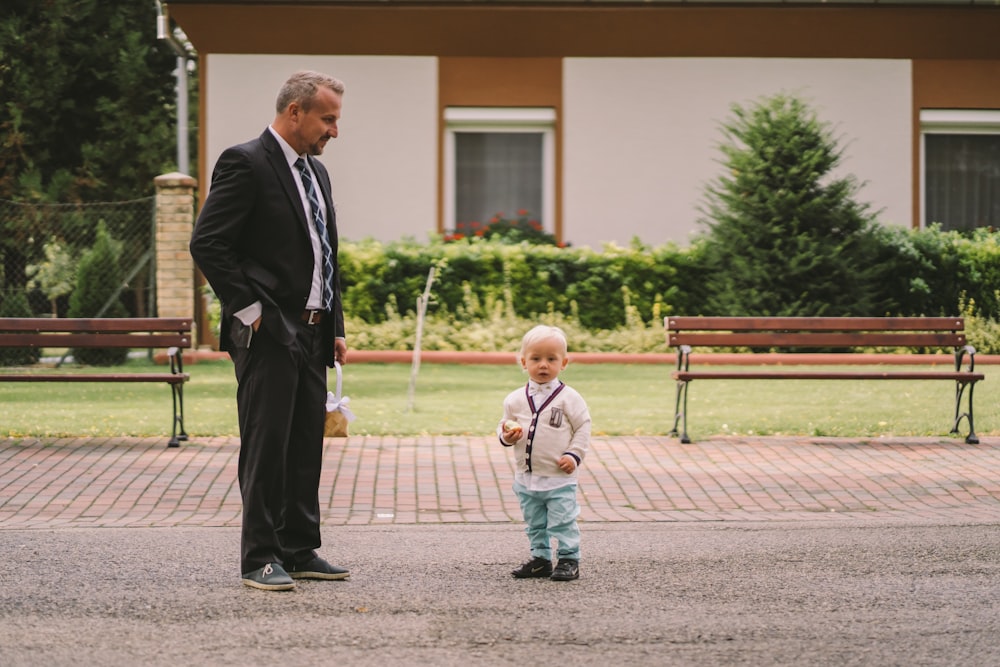 a little boy standing next to a man in a suit