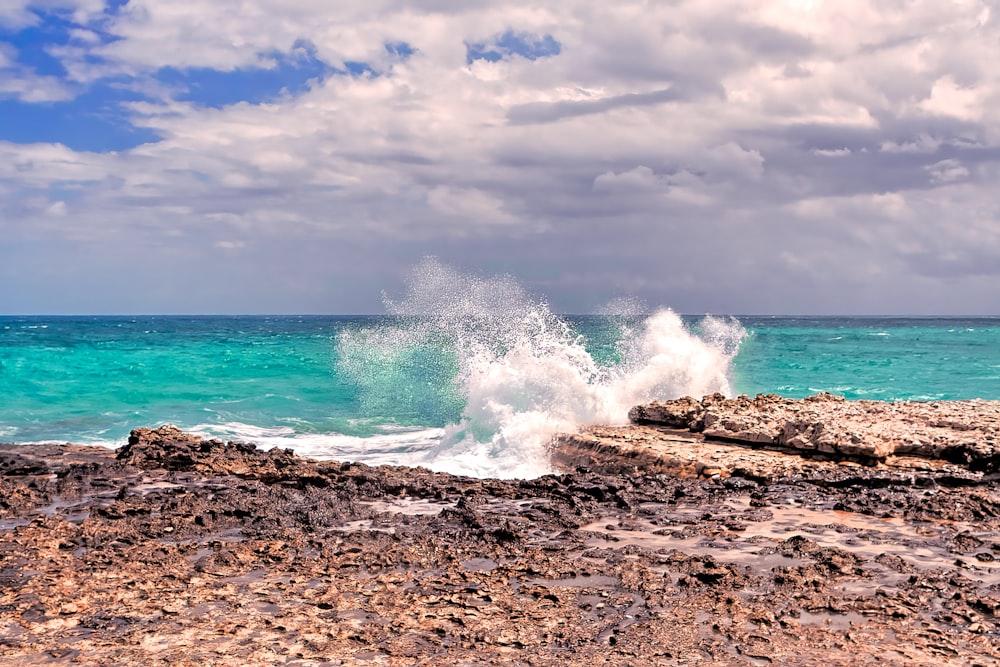 a wave crashing on a rocky shore on a cloudy day