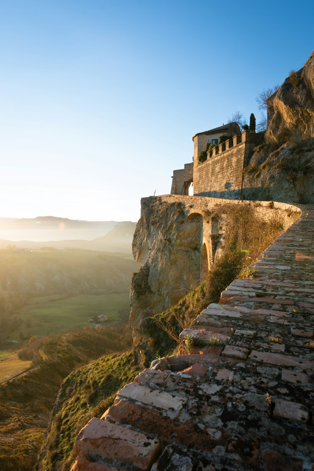 Una passerella di pietra che conduce a un edificio sulla cima di una montagna