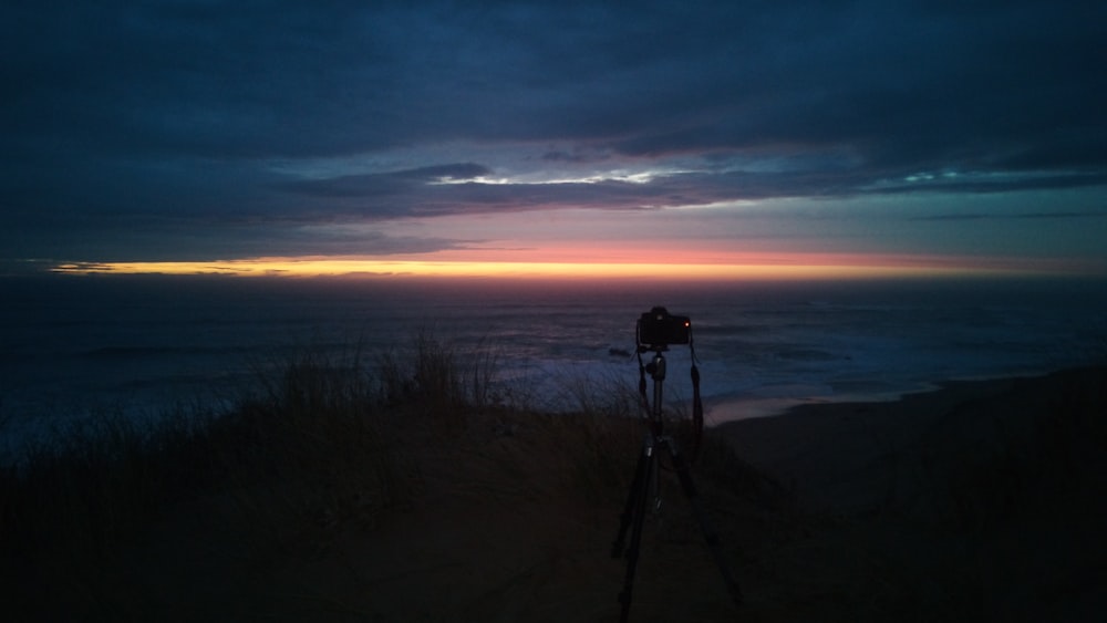 a tripod sitting on top of a hill next to the ocean