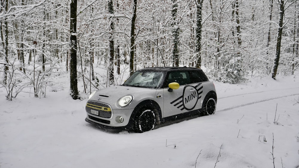 a small car driving through a snow covered forest