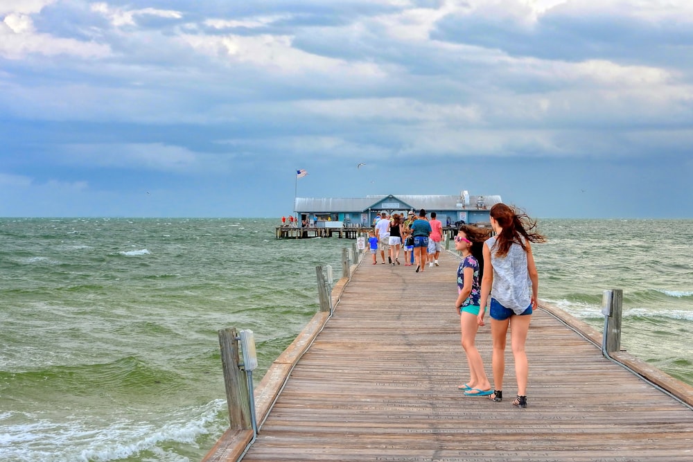 a group of people standing on a pier next to the ocean