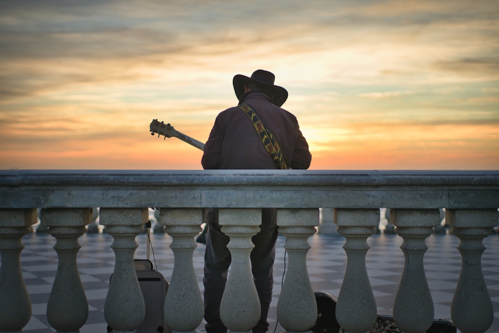 a man with a guitar sitting on a fence