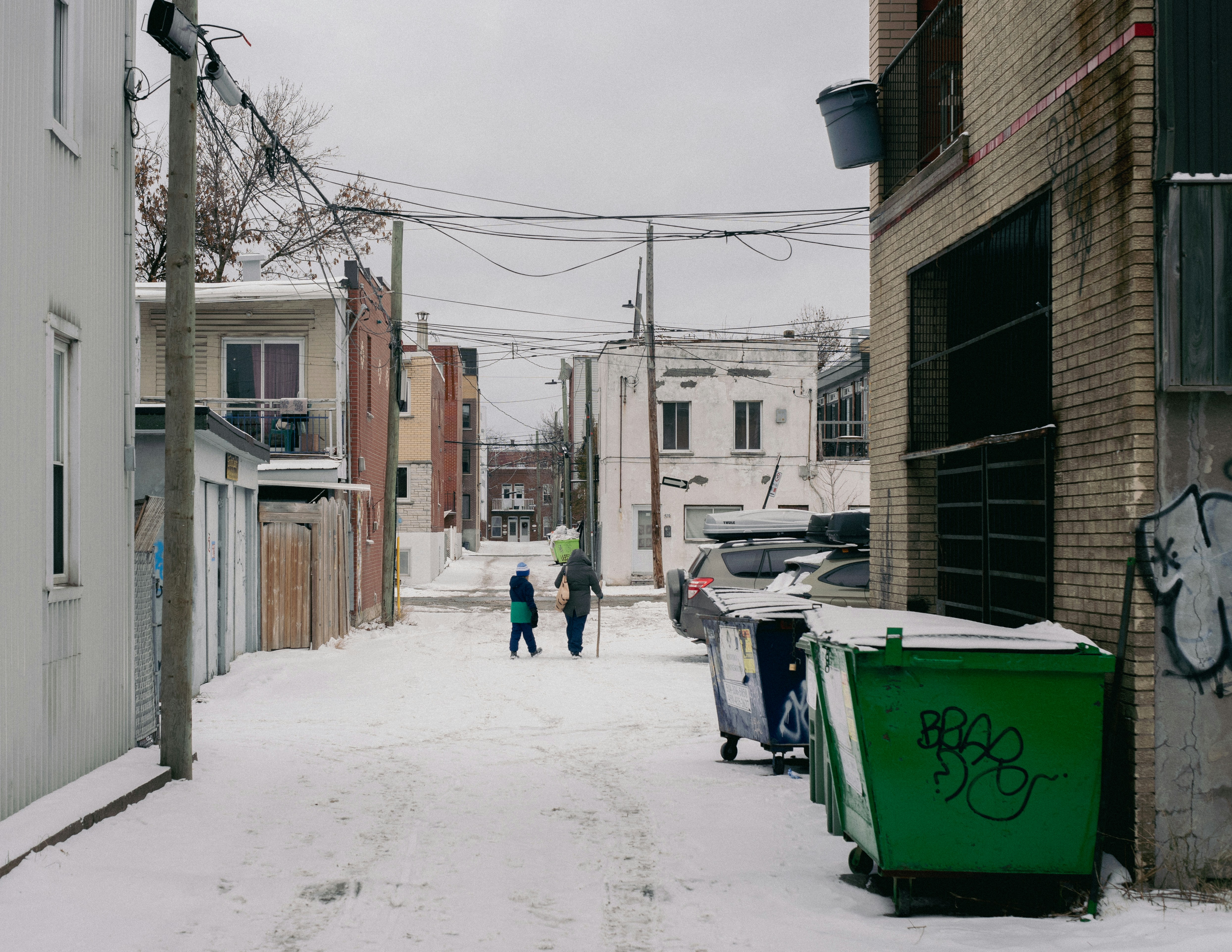 a couple of people walking down a snow covered street