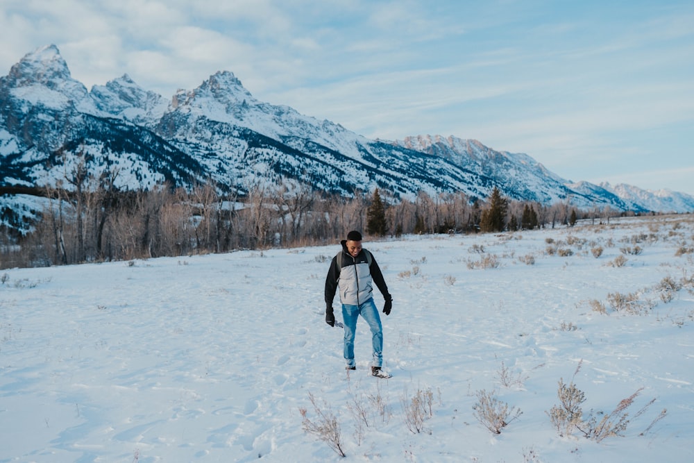 a man standing in the snow in front of mountains