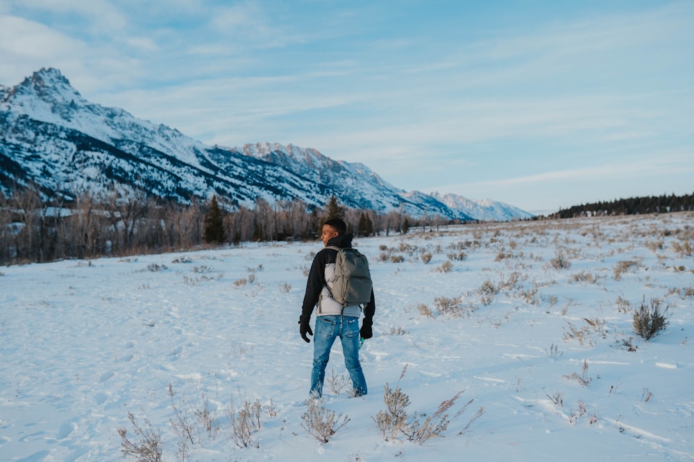 a person standing in the snow in front of a mountain