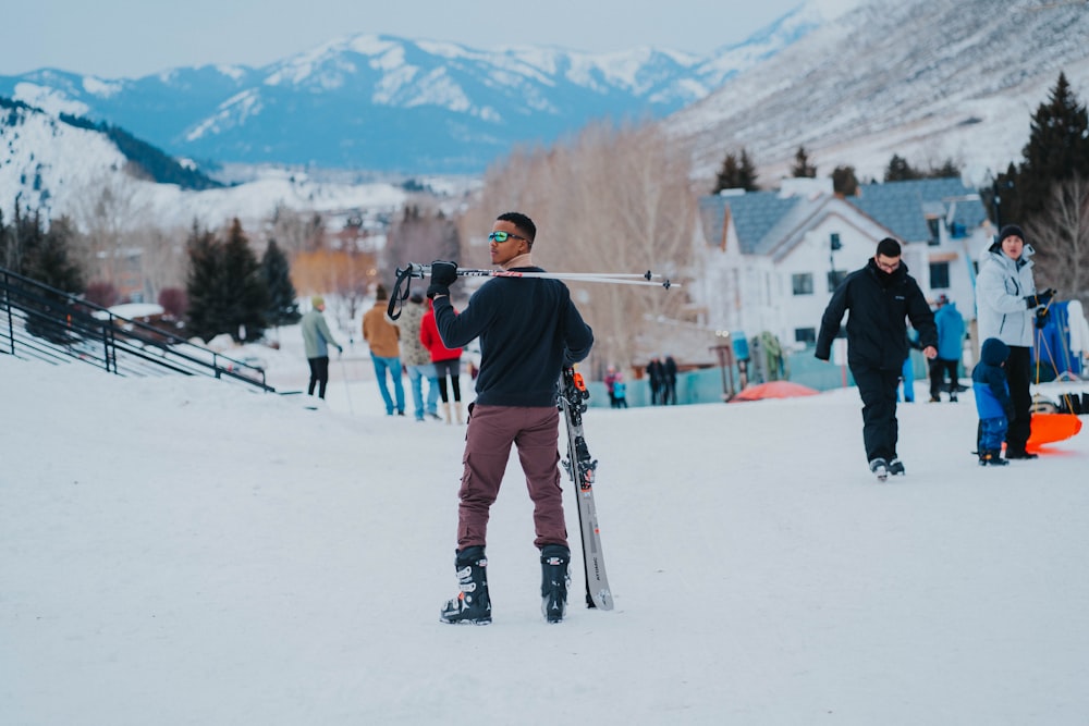 a man holding a pair of skis on top of a snow covered slope