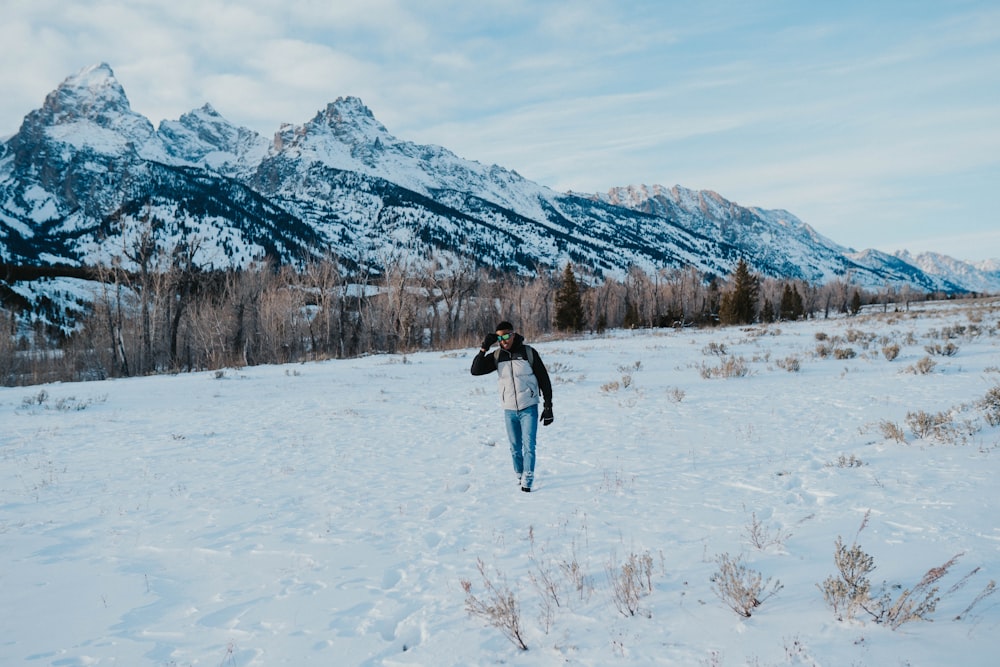 a person walking in the snow with a mountain in the background