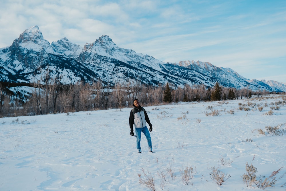 a man standing in the snow in front of a mountain