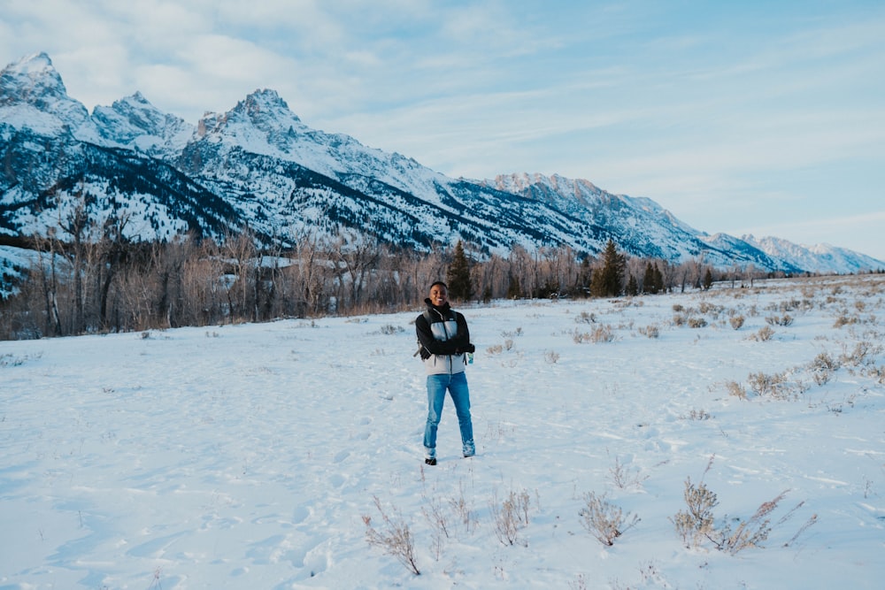 a person standing in the snow in front of mountains