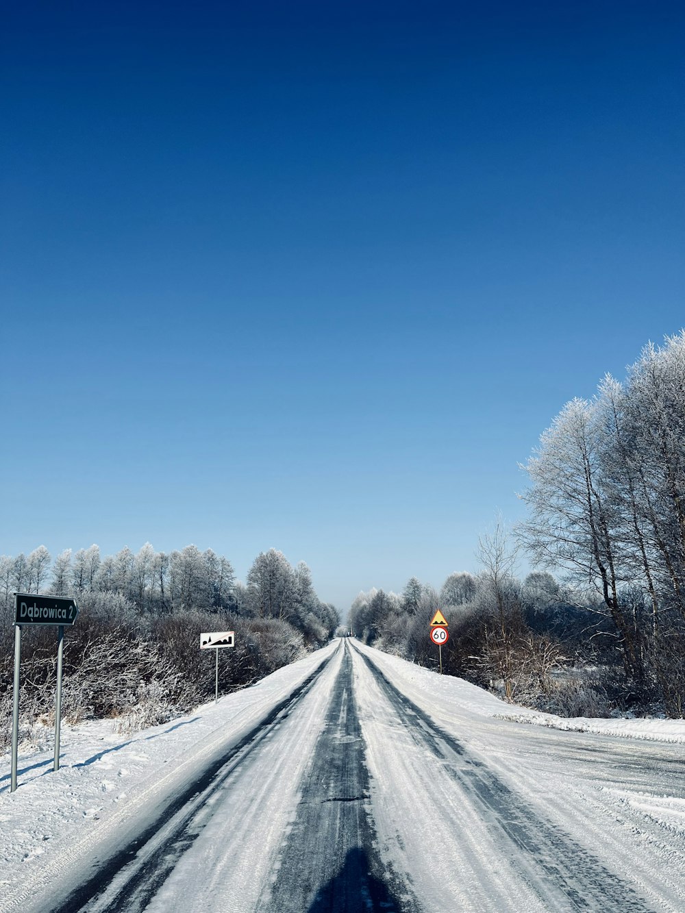 a snow covered road with a sign on the side of it