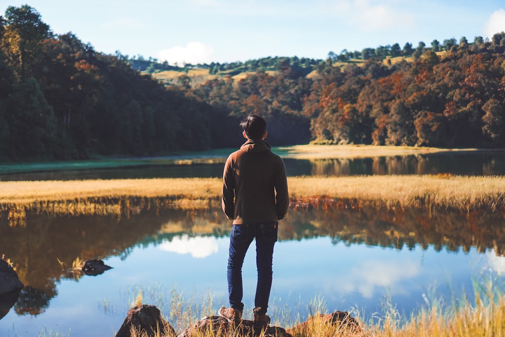 a man standing on top of a rock near a lake