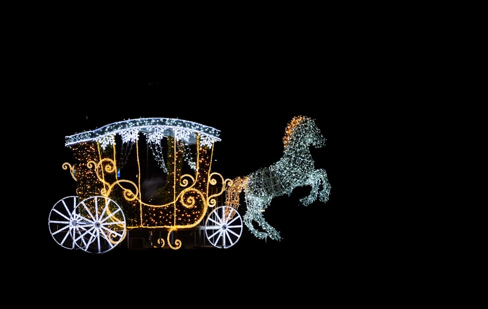 a horse drawn carriage is lit up at night
