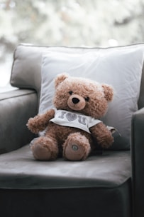 a brown teddy bear sitting on top of a couch