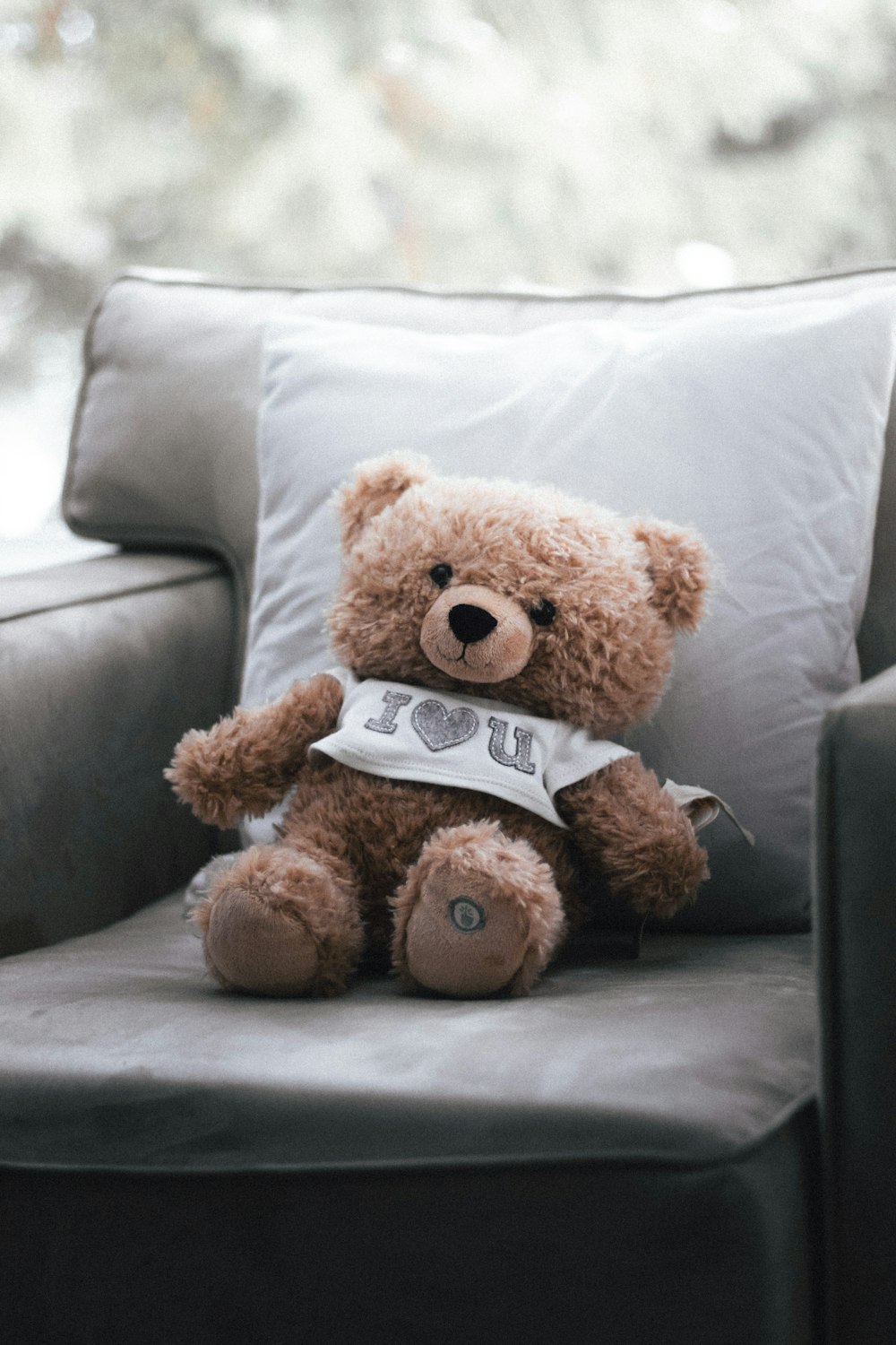 a brown teddy bear sitting on top of a couch