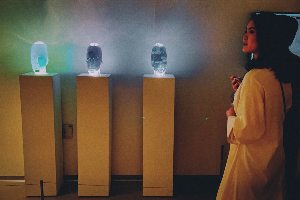 a woman standing in front of three illuminated vases