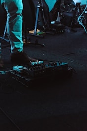 A moody studio shot of sadichist surrounded by instruments and recording gear.