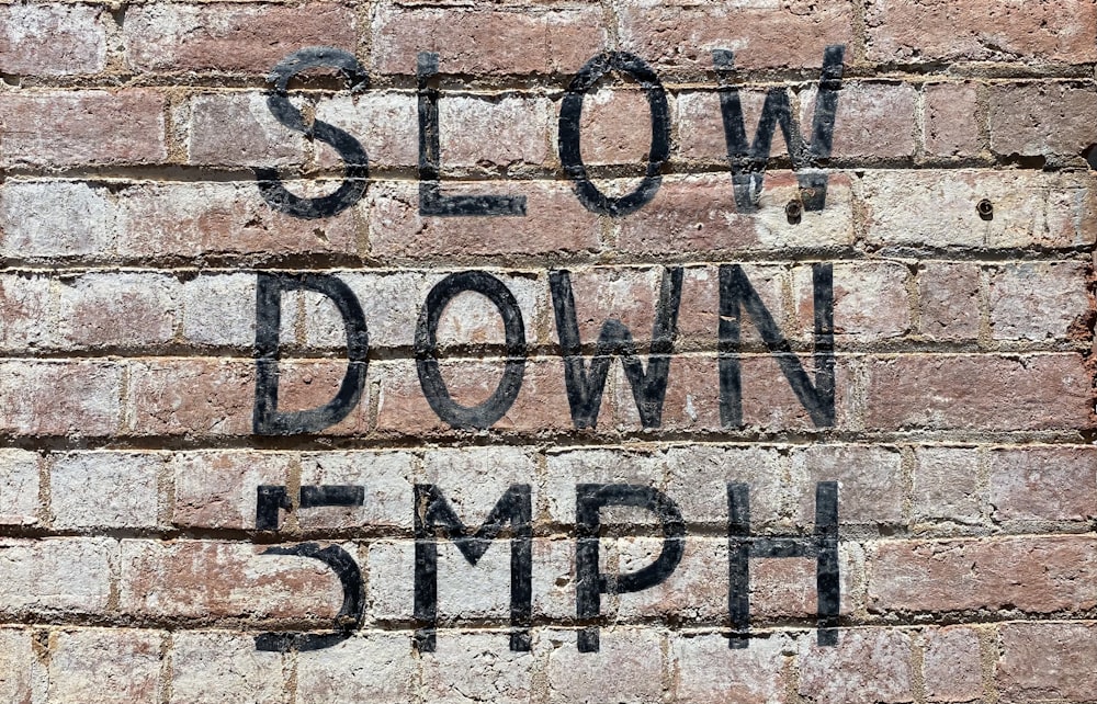 graffiti on a brick wall that says slow down and 5mph