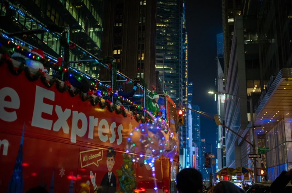 a red double decker bus driving down a city street