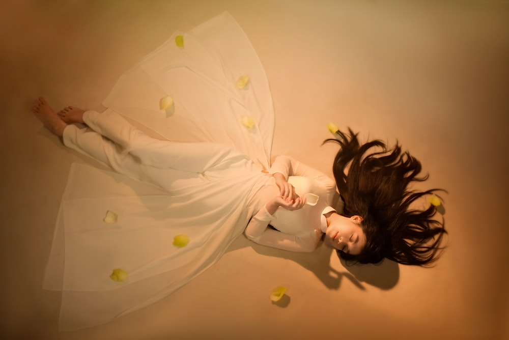 a woman in a white dress laying on the ground