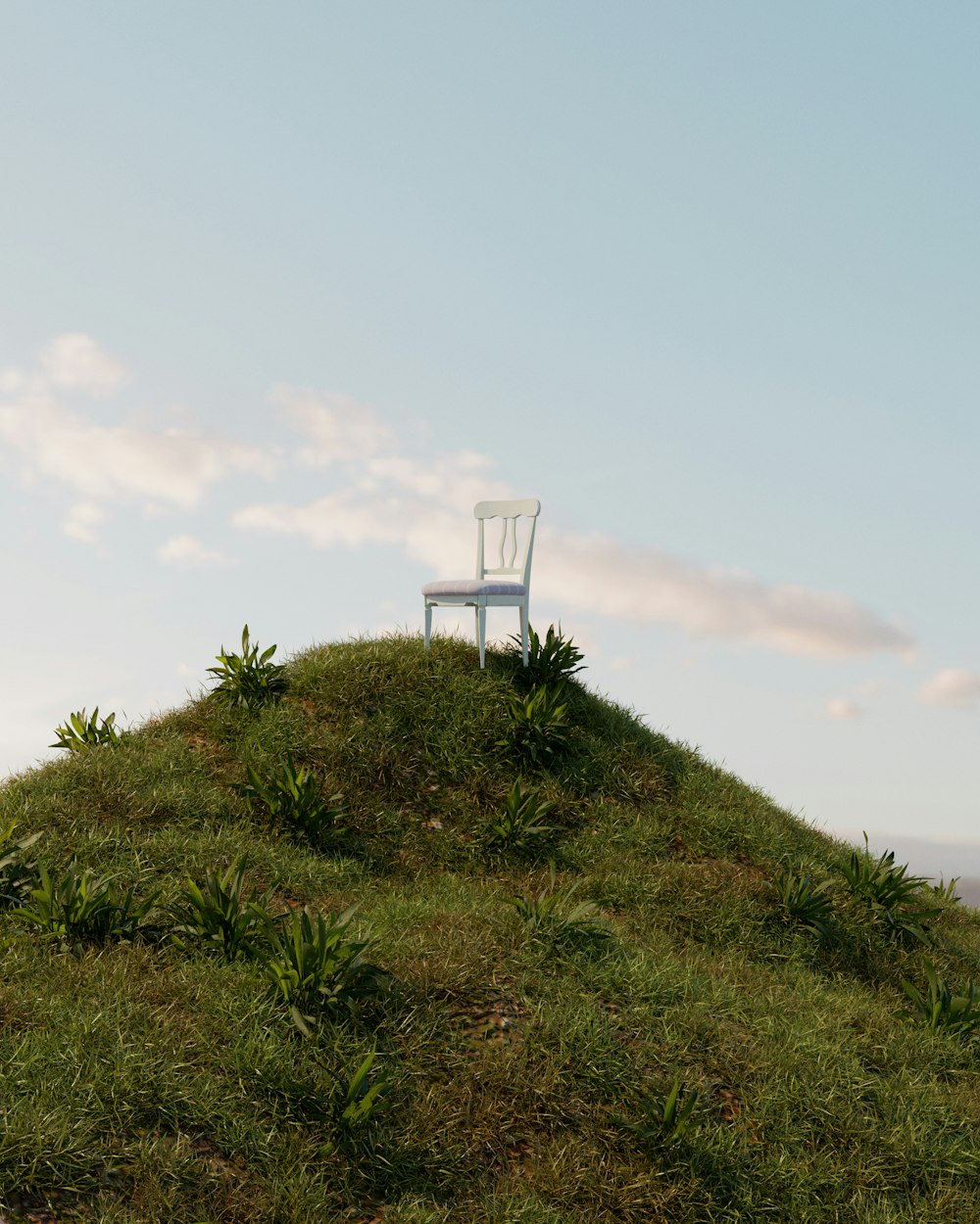 a white chair sitting on top of a grass covered hill