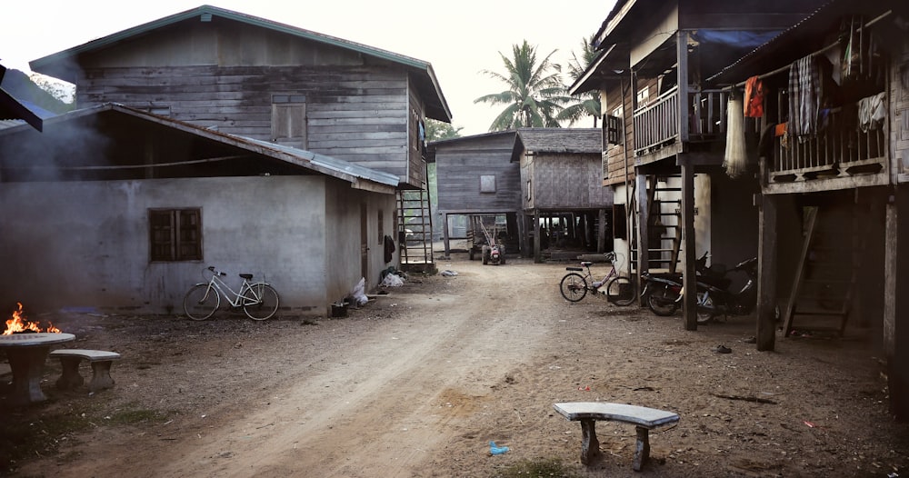 Un chemin de terre dans un village avec des bâtiments et des vélos