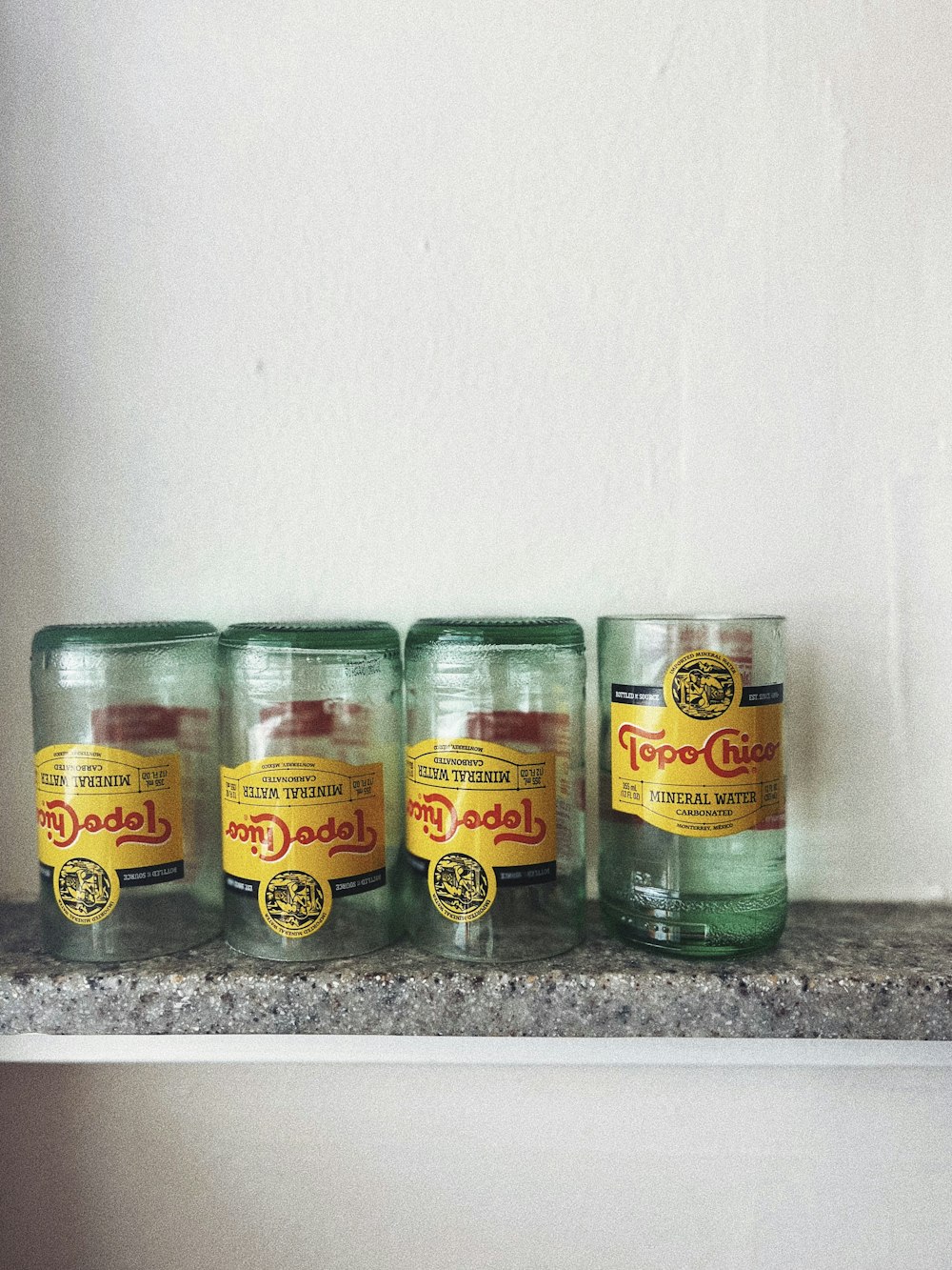 a shelf with three jars and a cup on top of it