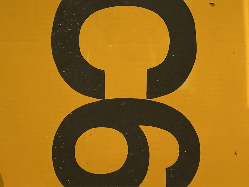 a close up of a yellow sign with a black letter