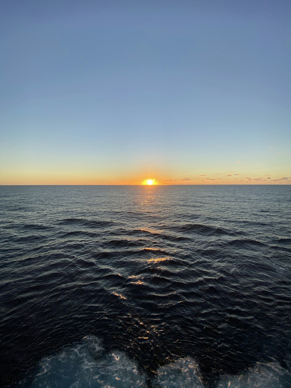 the sun is setting over the ocean as seen from a boat