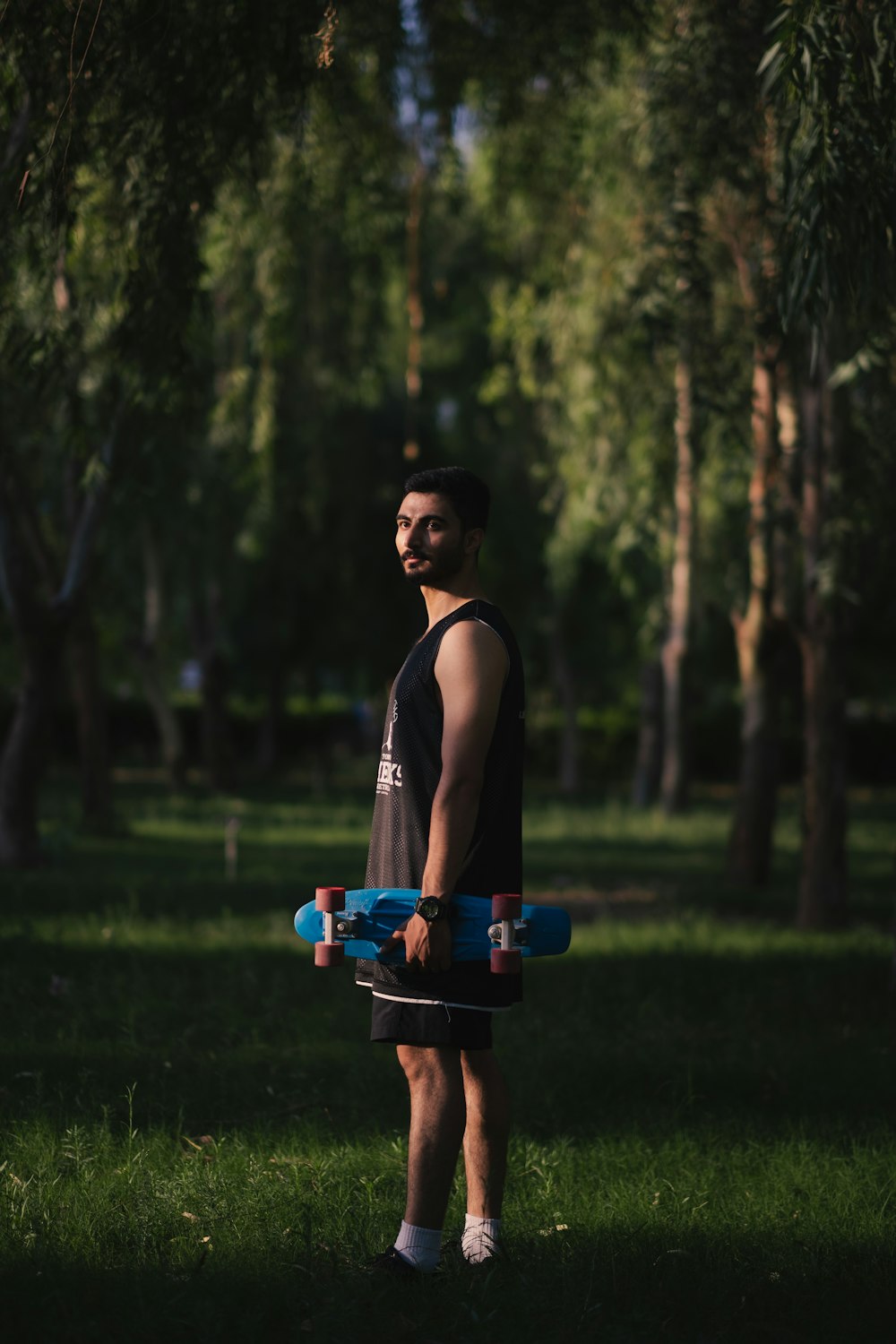 a man holding a skateboard in a park