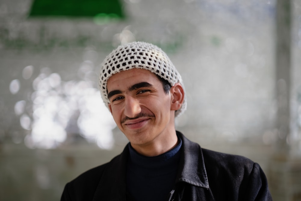 Un homme souriant portant un chapeau blanc et noir