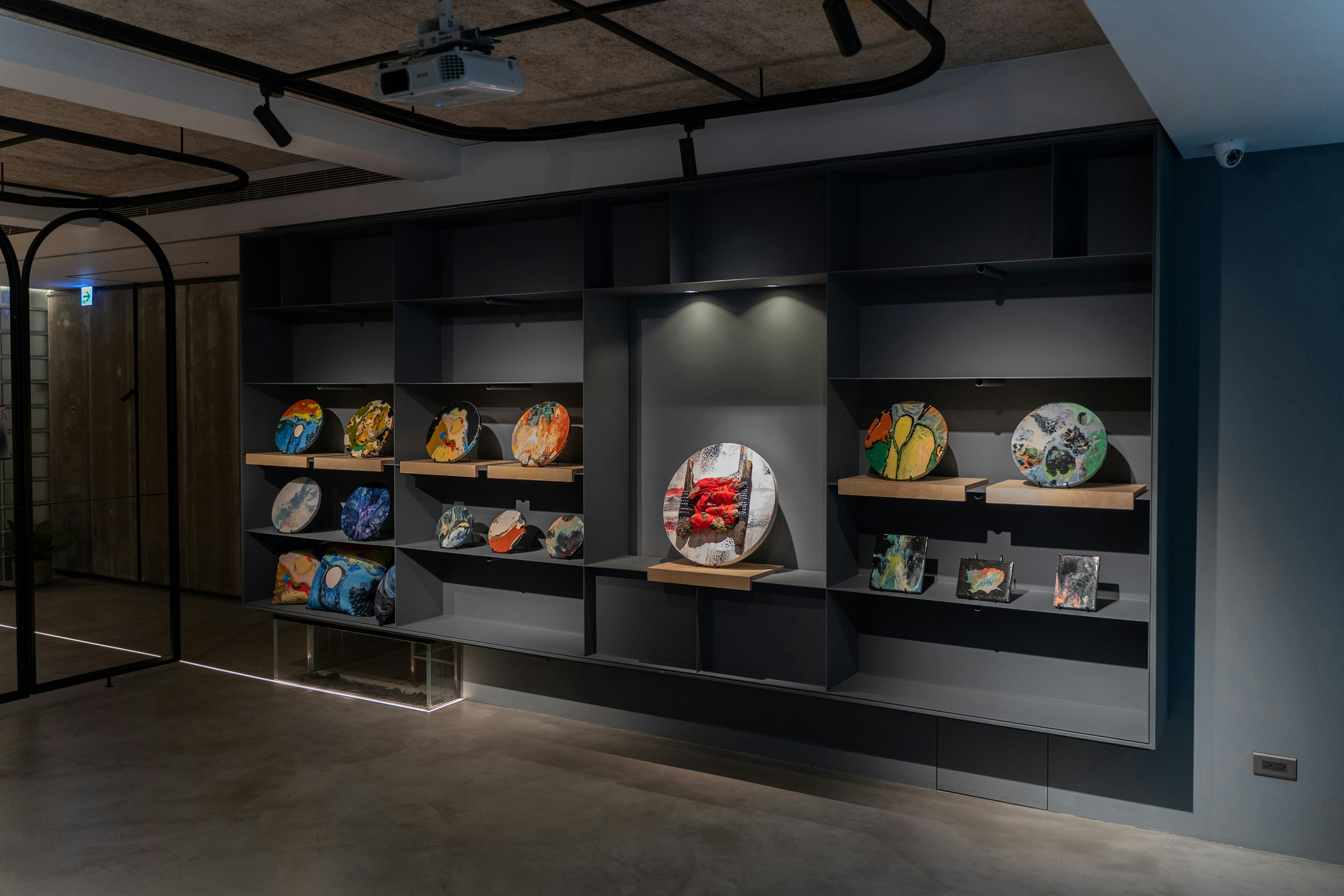 Museum gallery with ceramic artworks displayed on white walls, bright exhibition lighting, clean open space