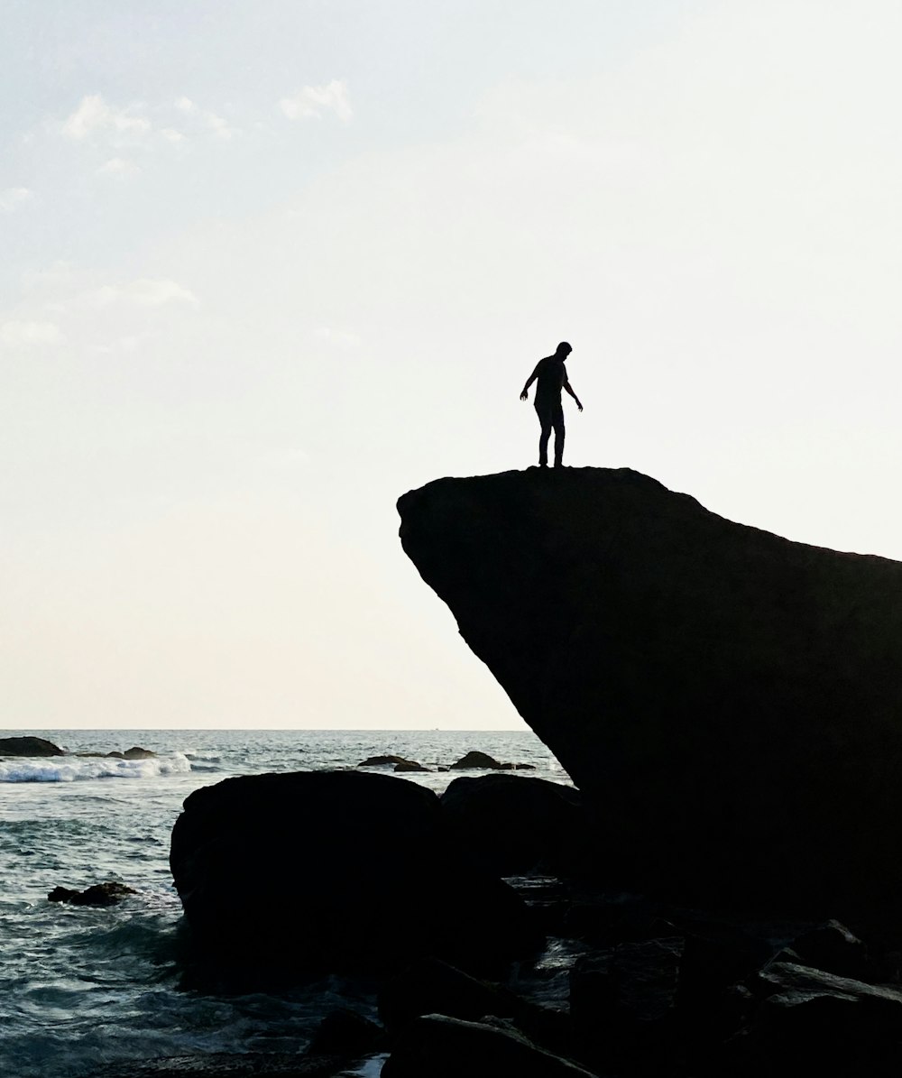 a person standing on top of a rock near the ocean