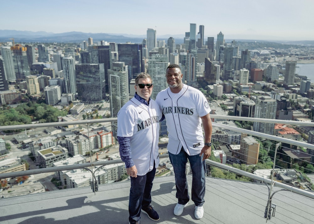 a couple of men standing next to each other on top of a building