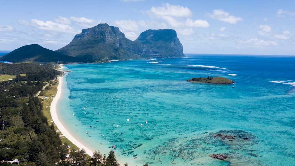 an aerial view of a beach with a mountain in the background