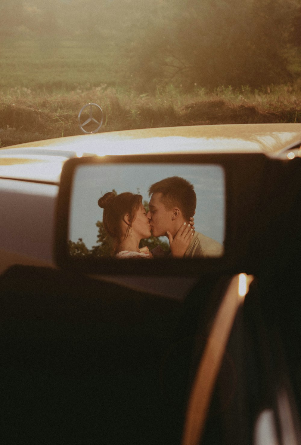 a man and a woman are kissing in a rear view mirror