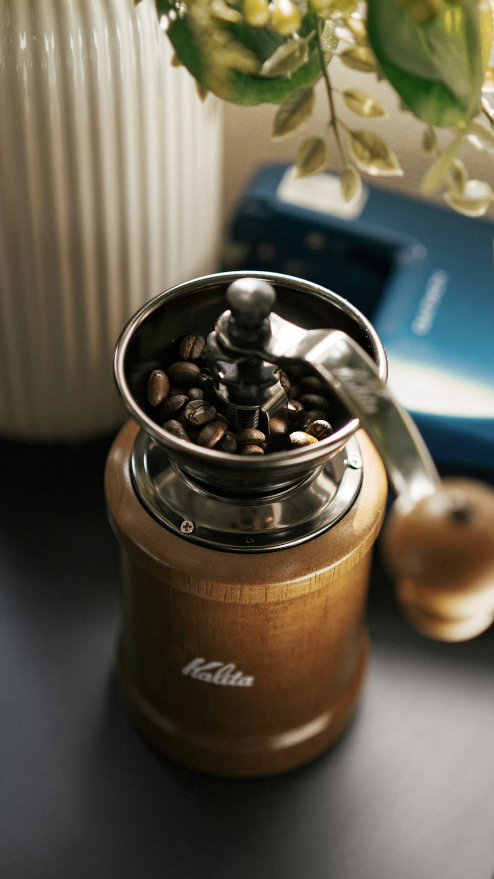 a coffee grinder sitting on top of a table next to a vase of flowers