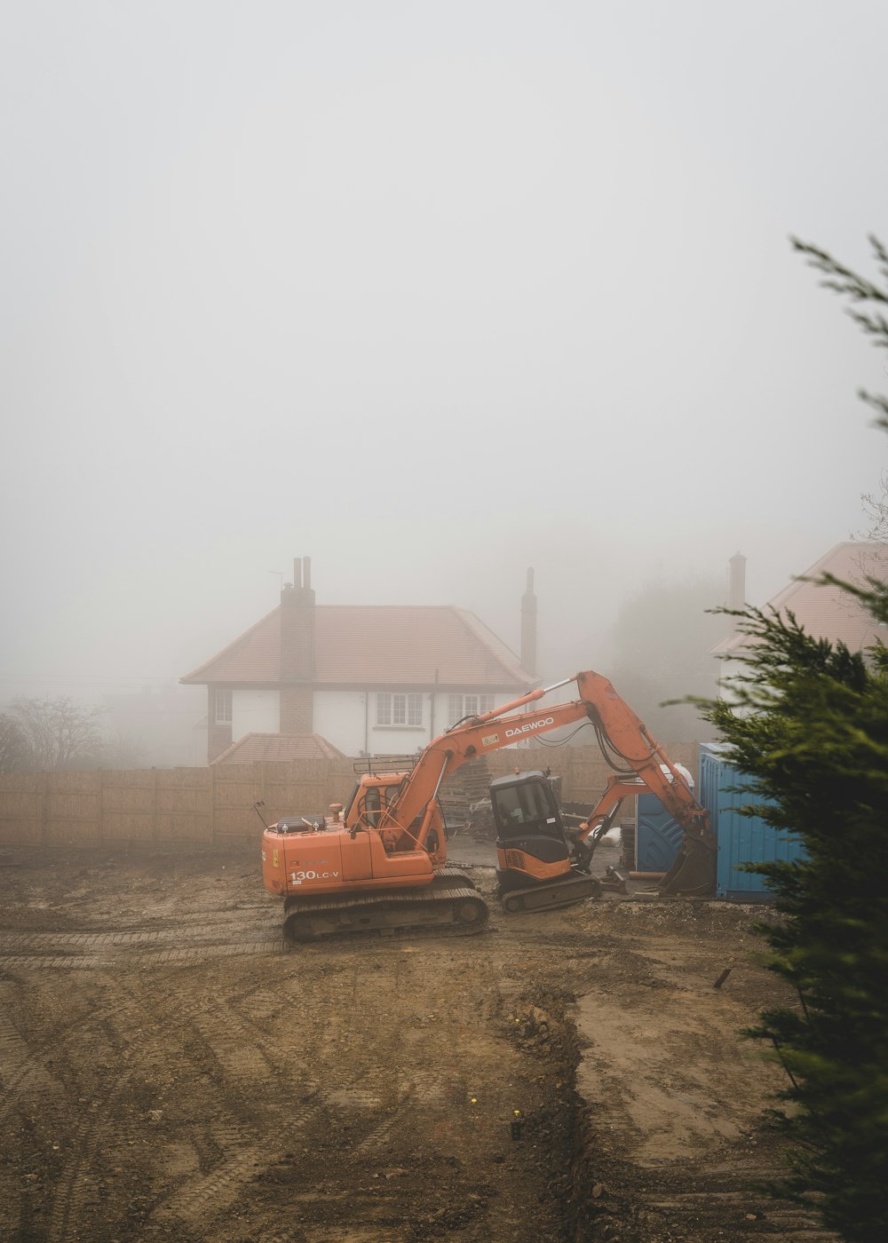 a construction site with a bulldozer and a house in the background