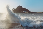 a large wave crashing into the shore of a beach