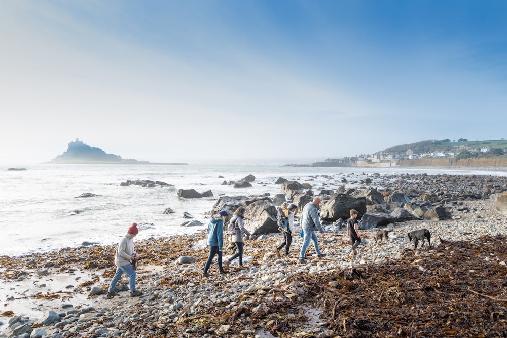 a group of people walking along a rocky beach