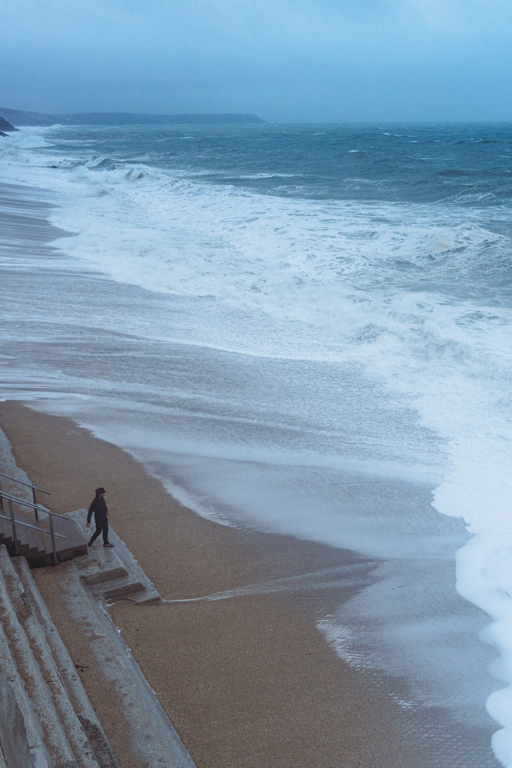 a man walking along a beach next to the ocean