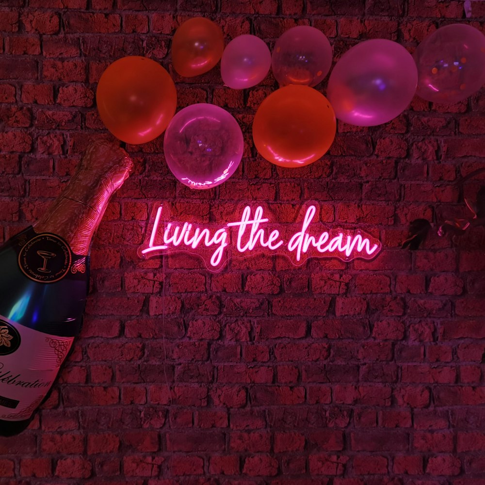 Eine Leuchtreklame mit der Aufschrift "Den Traum leben" neben einer Flasche Champagner