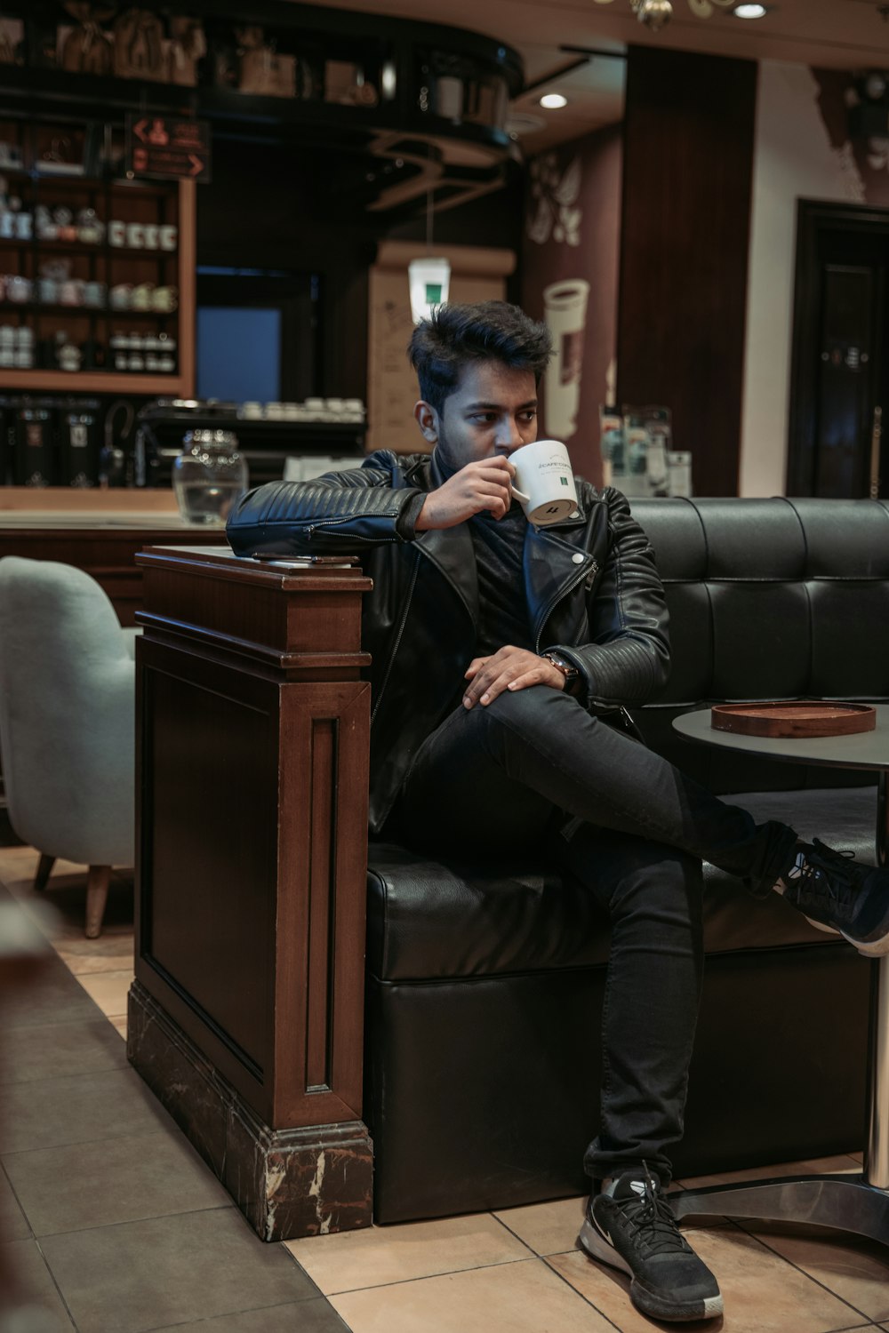 a man sitting on a chair drinking a cup of coffee