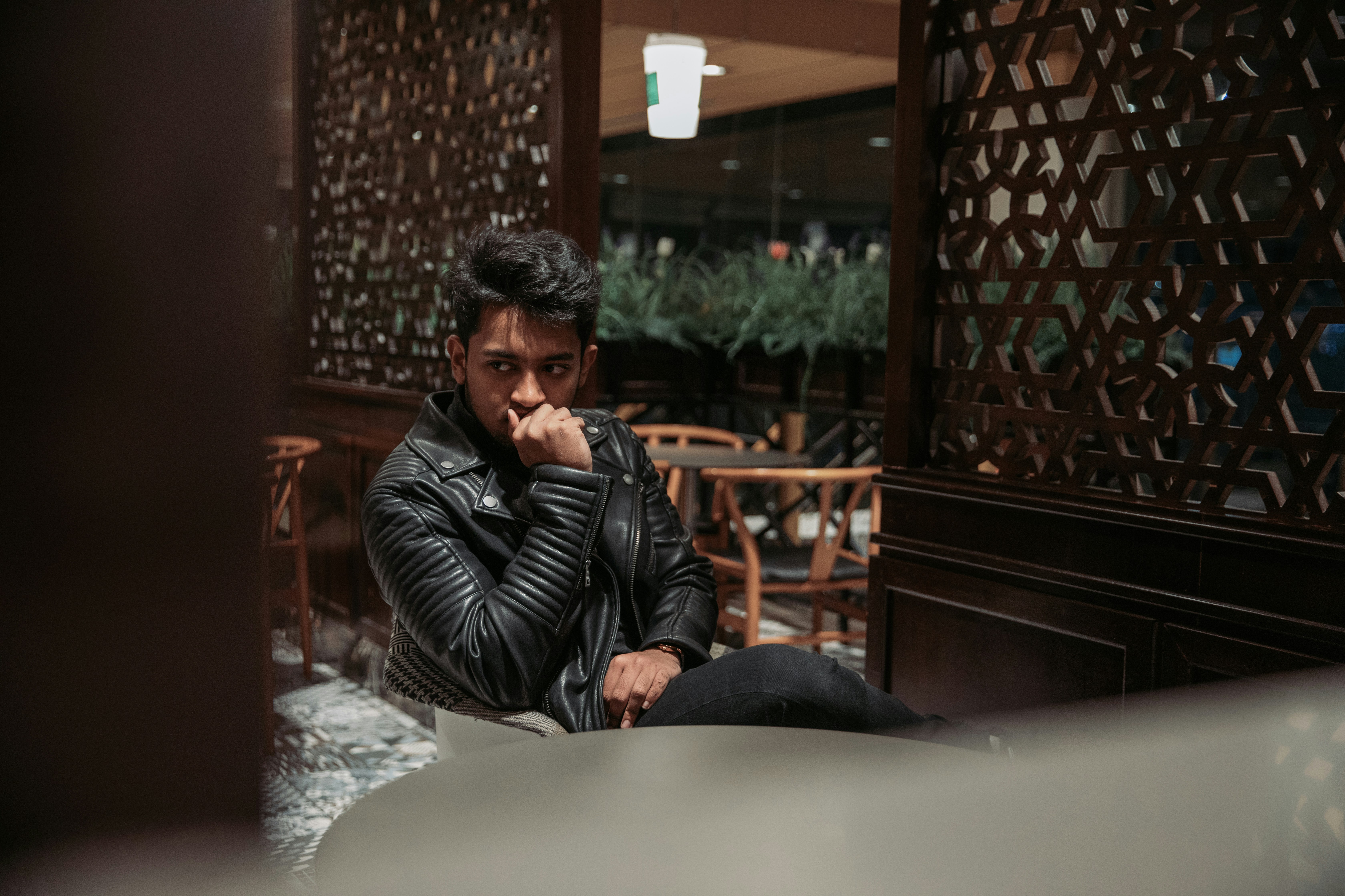 a man in a leather jacket sitting on a bench