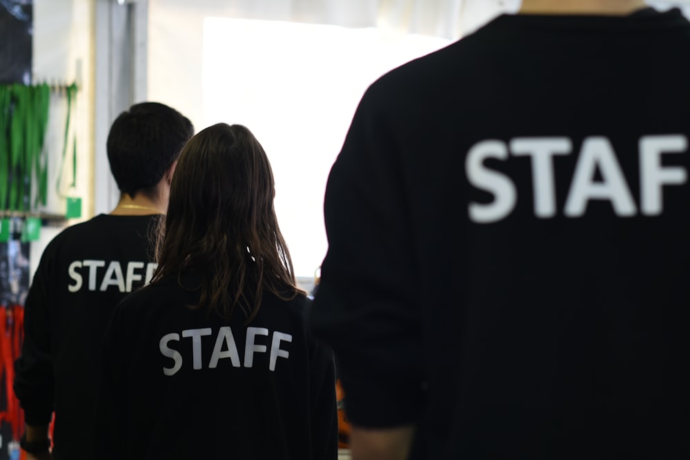 a group of people in black shirts standing in a room