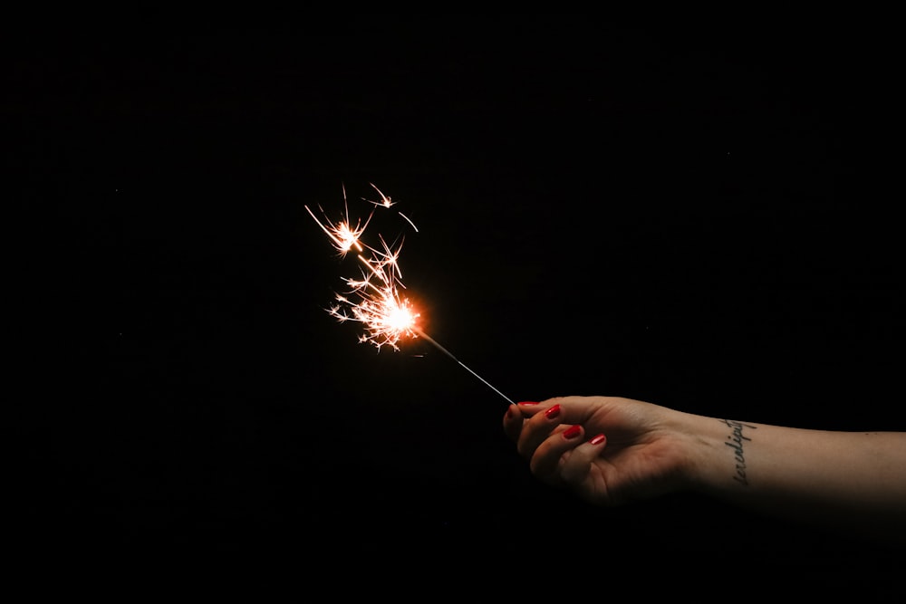 a hand holding a sparkler in the dark