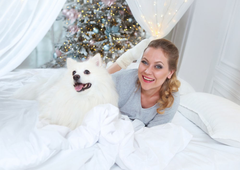 a woman laying in bed with a white dog