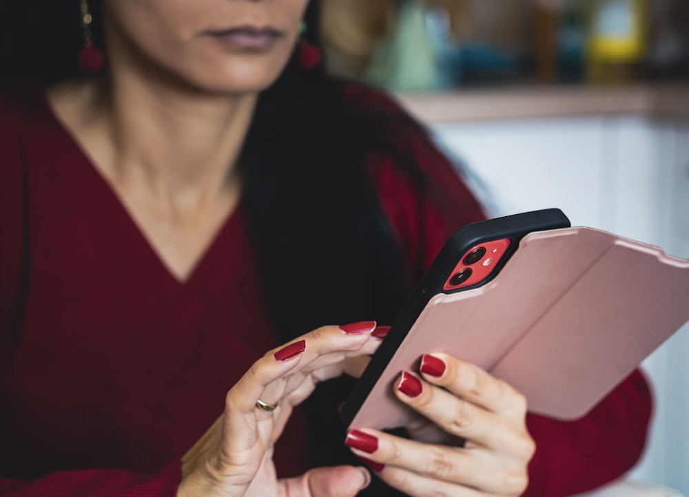 a woman in a red sweater is looking at a tablet